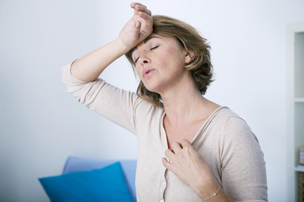 Woman with the back of her hand on her forehead because she has menopause and varicose veins.
