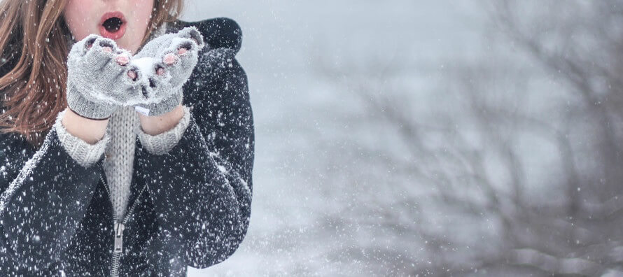 A woman blowing snow out of her gloved hands. How winter impacts your veins.