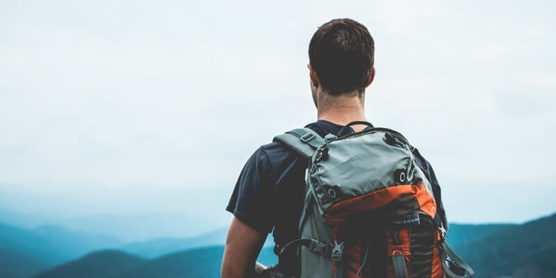 A man with a backpack looking out over mountains, thinking about diabetes and varicose veins.