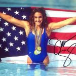 An Olympic swimmer, who has varicose veins, with medals and the American flag--in a pool.