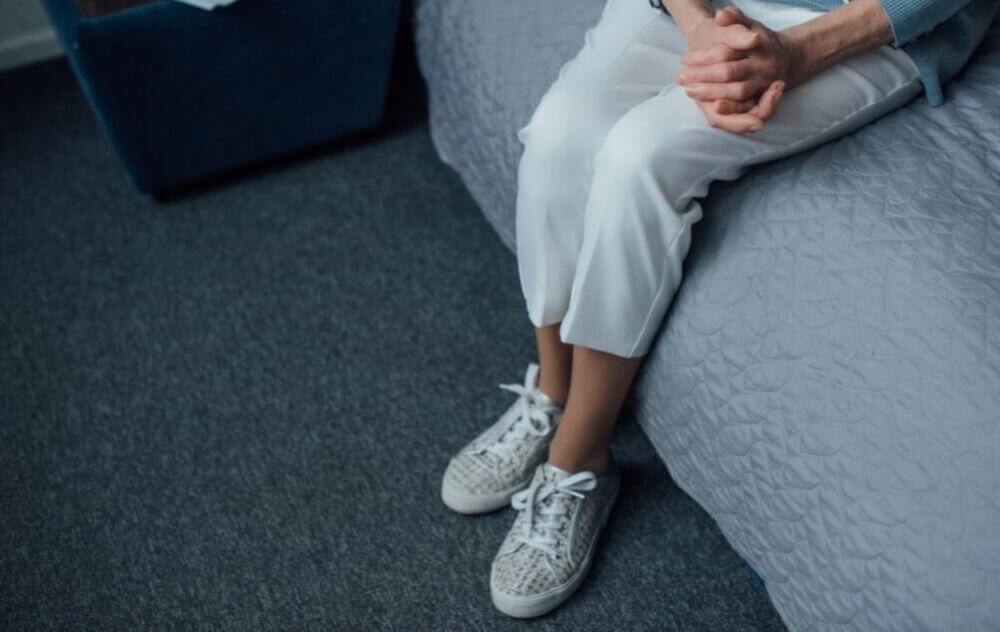 woman sitting on bed wishing that her varicose veins would go away on their own
