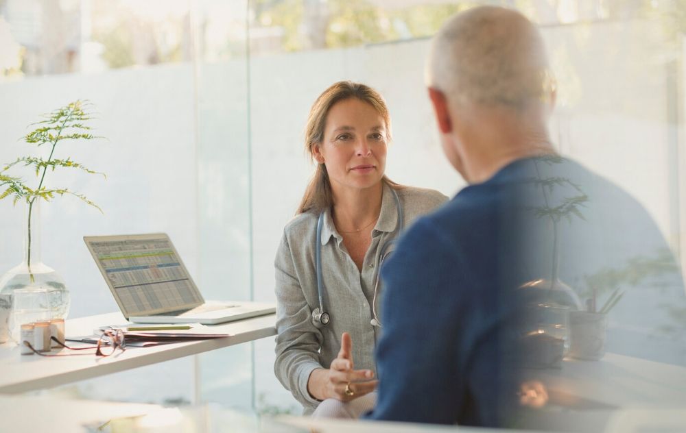 doctor talking to male patient about his vein treatment options