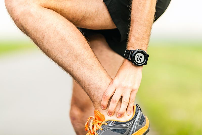 Man massaging sore calf and Achilles tendon during workout