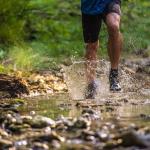 man running through the woods over a stream