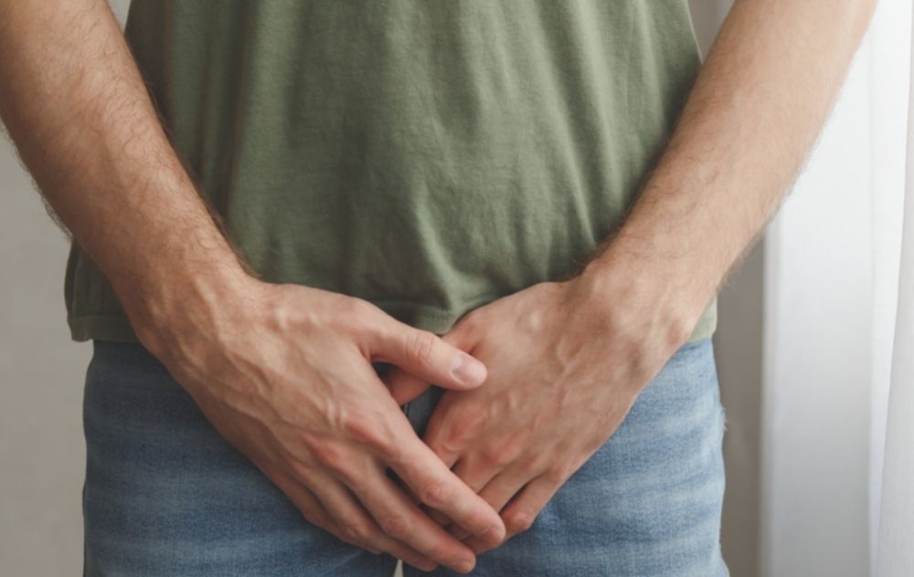 Man covering his hands over his scrotum