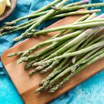asparagus on cutting board with lemon wedges