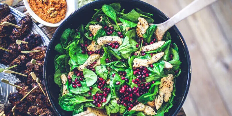 Bowl of spinach, chicken, and cranberry salad: food to improve circulation.