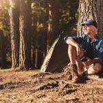 man sitting next to a tree camping