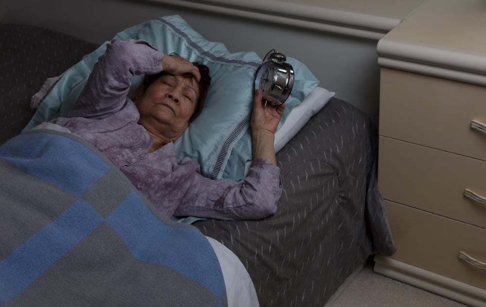 Best Ways To Improve Circulation In Legs While Sleeping 5 Woman having trouble sleeping at night time due to poor circulation related discomfort in the legs.