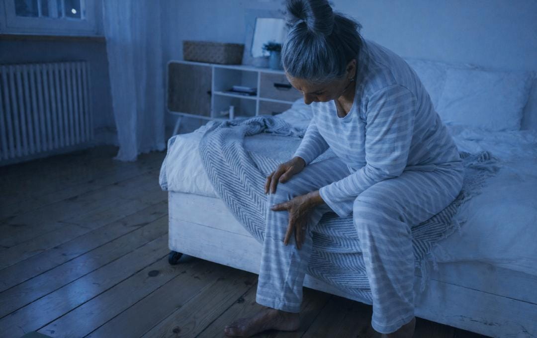 Leg Pain At Night: Could Varicose Veins Be The Cause? 4 Older woman is at the foot of her bed at night because her leg hurts.