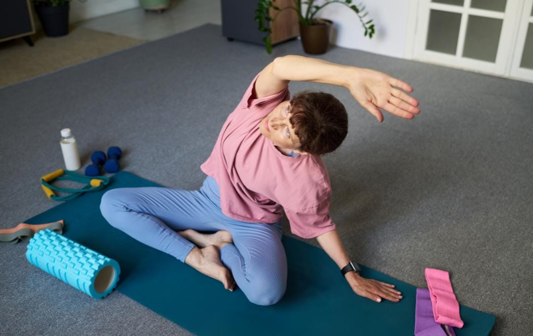 Can You Get Varicose Veins From Working Out? 6 Older woman sits cross-legged on her yoga mat. She stretches her upper body, which helps with circulation and varicose veins.